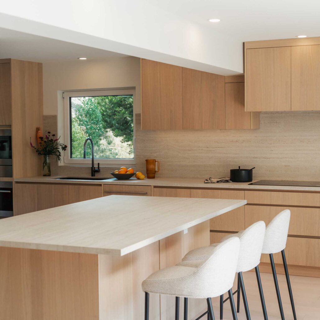 Combined kitchen and dining area with natural wood finishes and modern lighting.