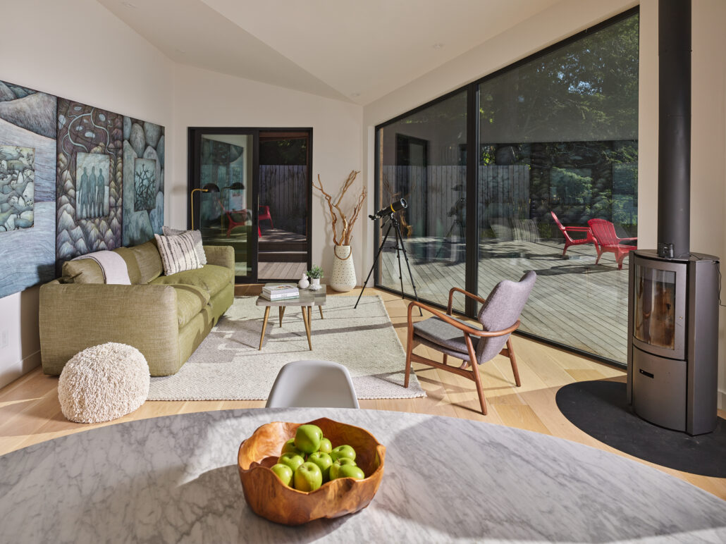 Bright living room with modern furnishings and glass wall overlooking nature.