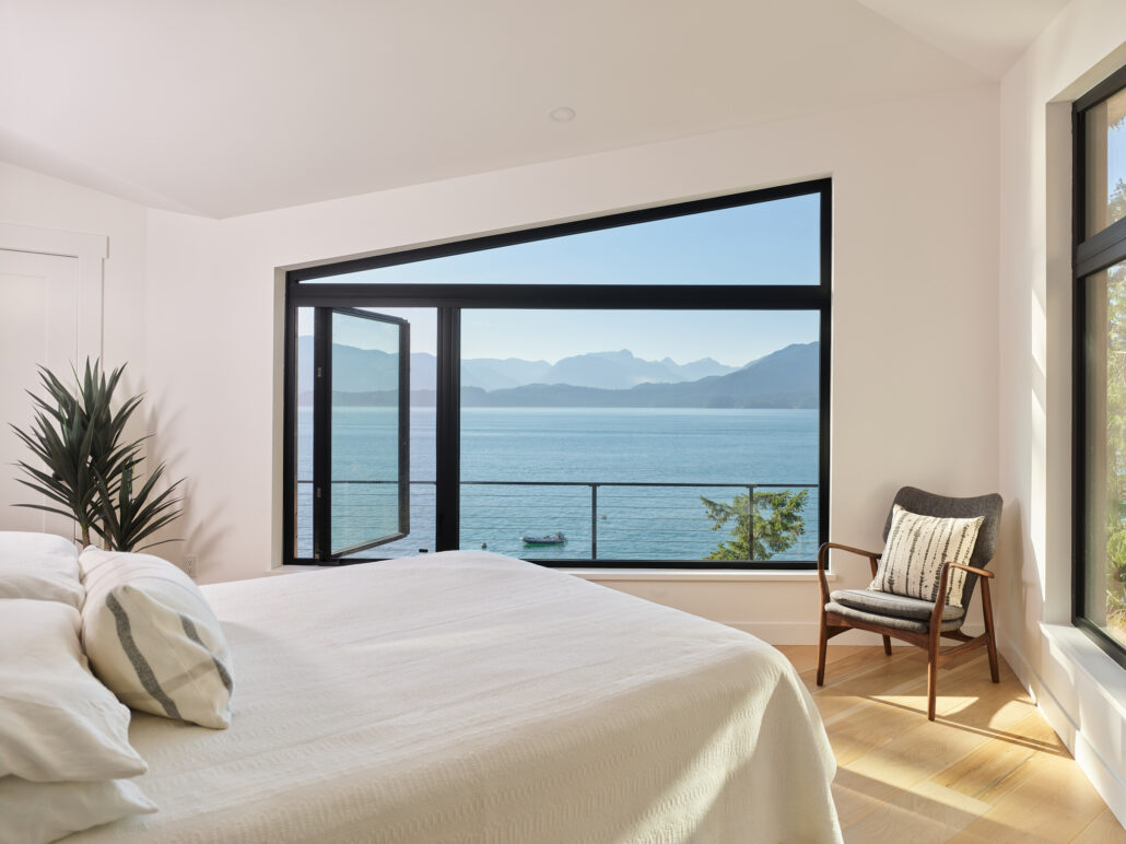 Light-filled bedroom with folding glass doors opening to an oceanfront patio.