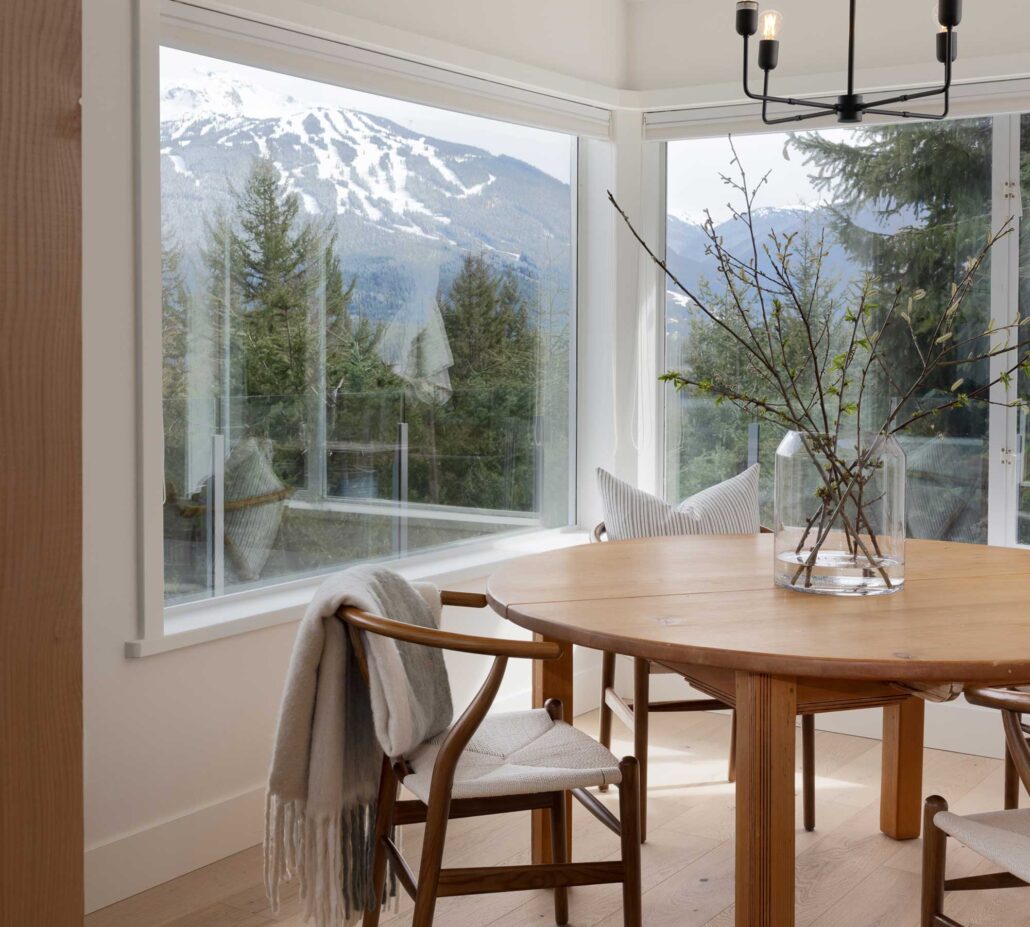 Dining area with large windows framing mountain views and natural light in a Whistler home