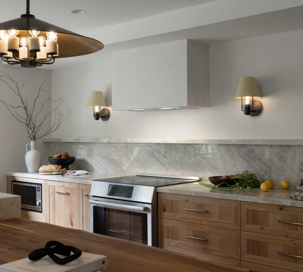 Contemporary kitchen with white stone countertops, warm oak cabinetry, and custom lighting in a Whistler mountain home.